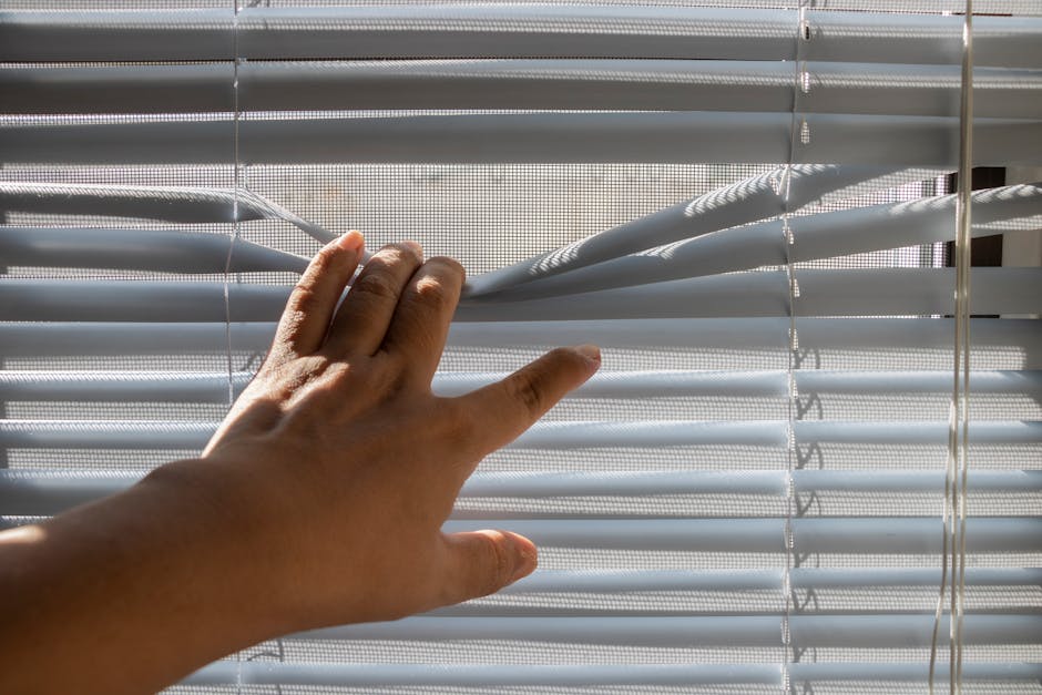 Professional installing custom window blinds in a bright, modern home